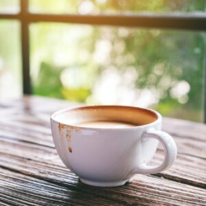 A white mug of hot coffee on wooden table in the morning