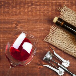 Bottle of wine and cork and corkscrew on wooden table