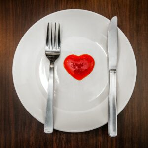 Top view of fork and knife with ketchup on white plate laid flat on wooden tabletop